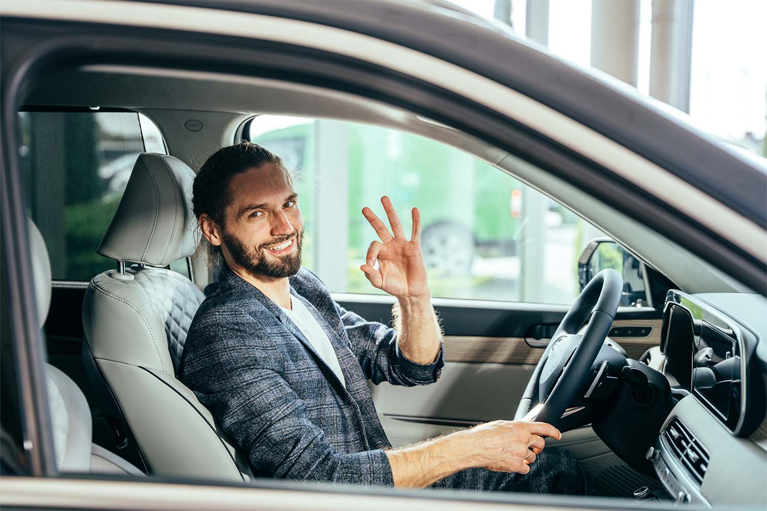 Mann sitzt im Auto und gibt OK-Sign